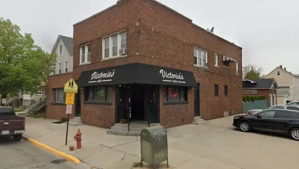 Street view of Victoria’s lounge with black awning on a corner brick building in Cicero, IL near a residential neighborhood